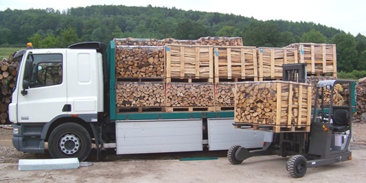 Chargement de palettes de bûches par le chariot qui sera embarqué pour la livraison