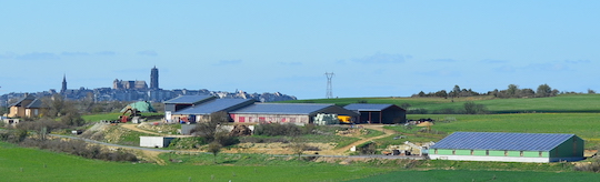 Vue de la ferme Chayriguès à Flavin, avec le hangar à plaquettes et son toit photovoltaïque à droite et en fond la cathédrale de Rodez, photo Frédéric Douard